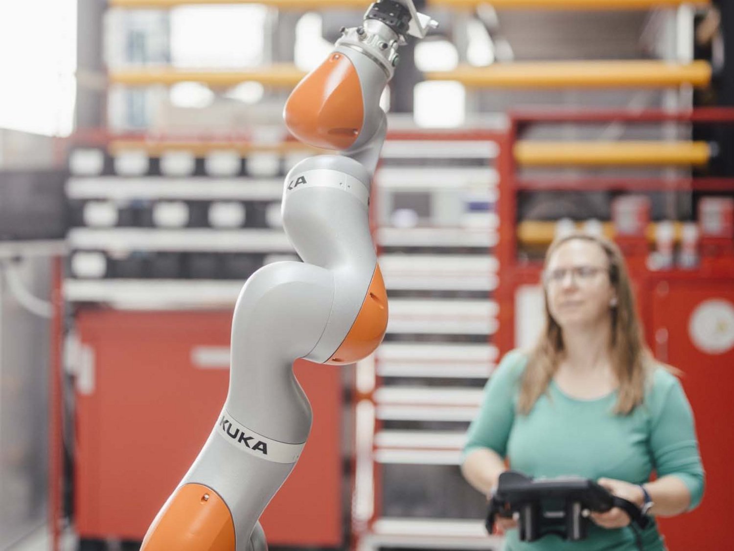 Ein Mensch steht neben einem Roboter in einer Fabrik.