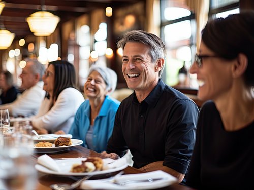 Man sieht eine Gruppe von Freunden, die in einem Restaurant eine Mahlzeit genießen und dabei fröhliche Gespräche, Lachen und Zusammengehörigkeit zeigen.